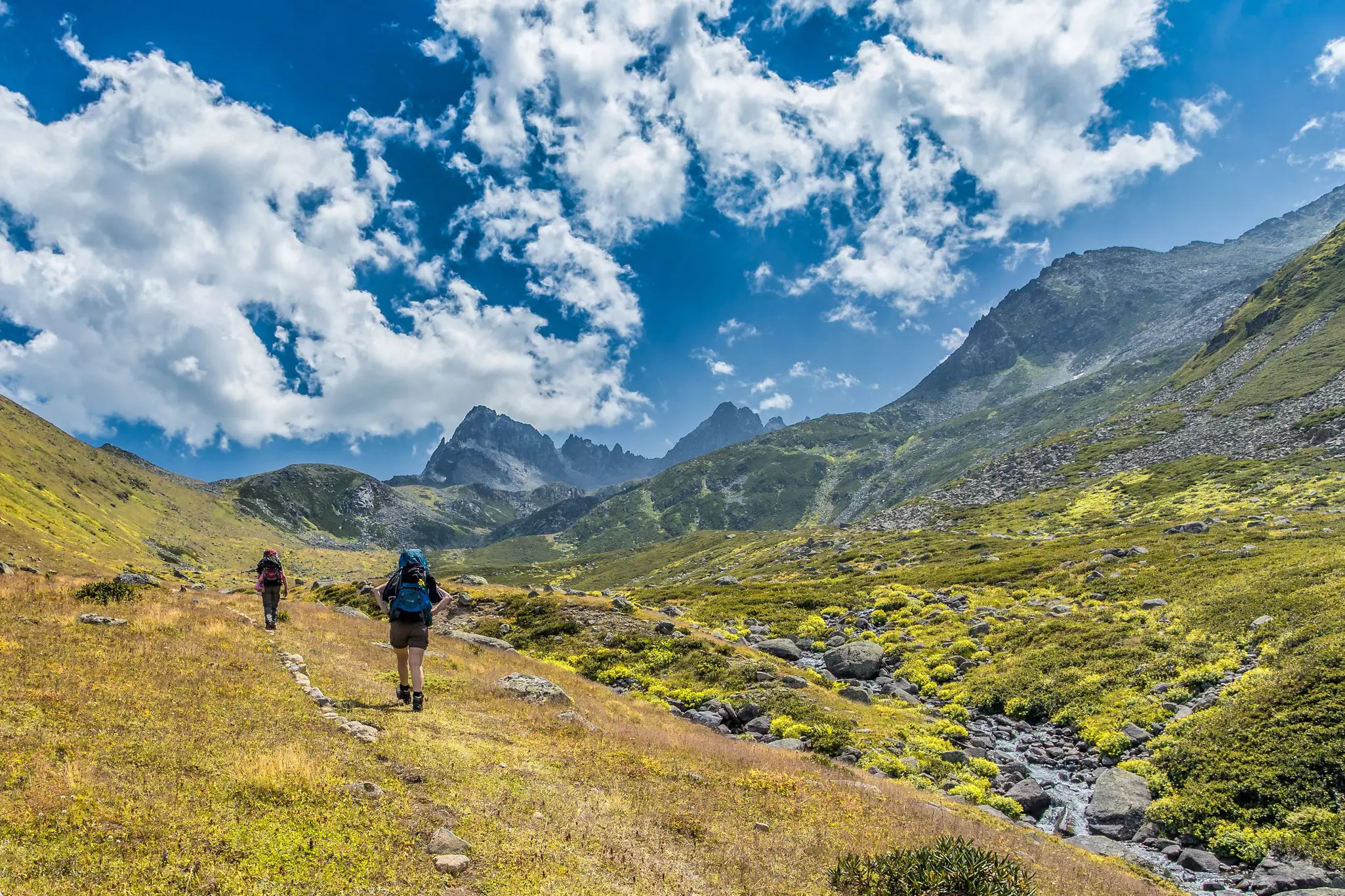 Two hikers follow a scenic trail in mountain scenery in Turkey.
