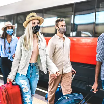 Multiracial friends group walking at railway station platform - New normal travel concept with young travelers on social distancing and face covered by protective mask - Focus on blonde girl with hat