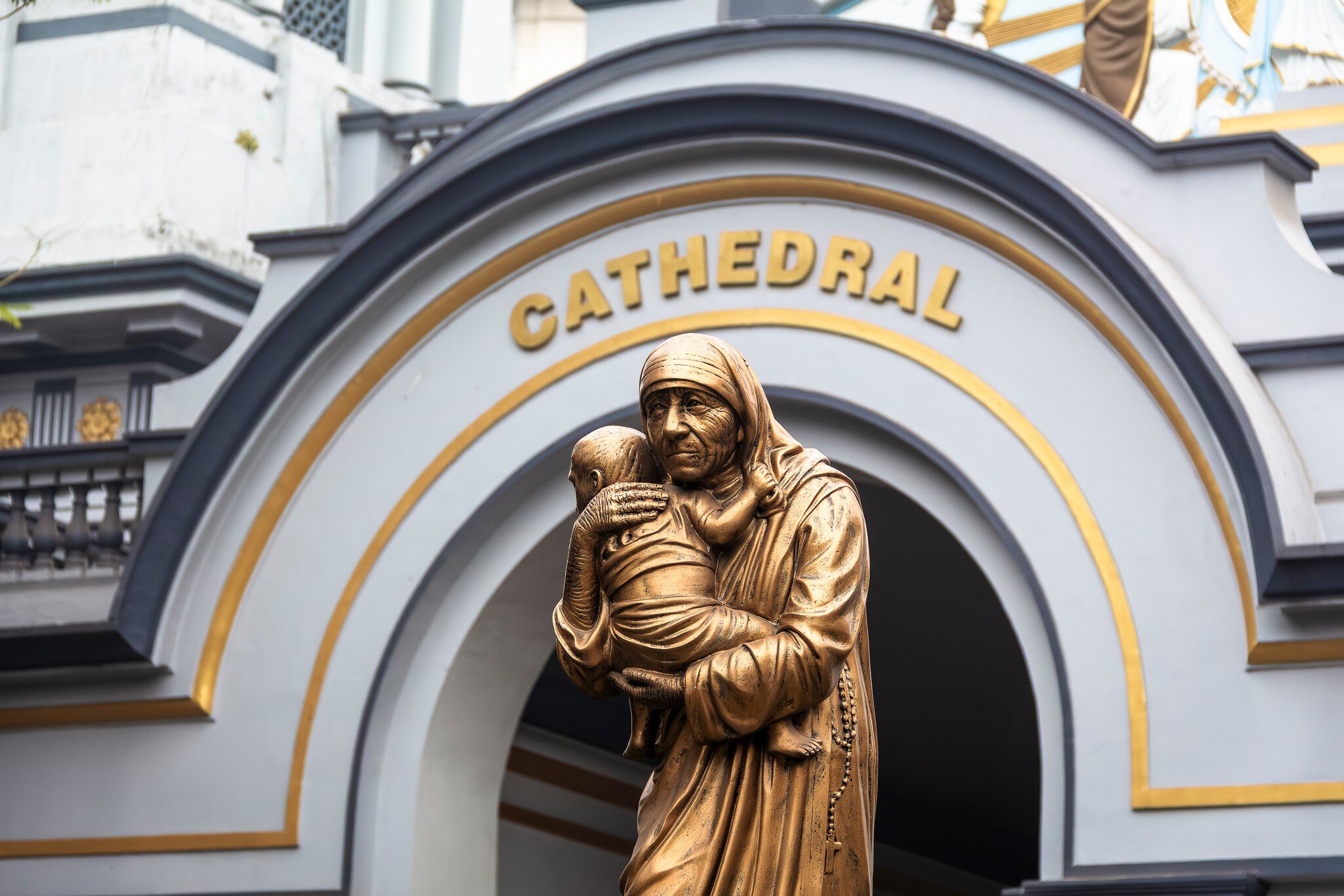 Detail of a gold statue in front of the facade of the Holy Rosary Cathedral in Kolkata, India.