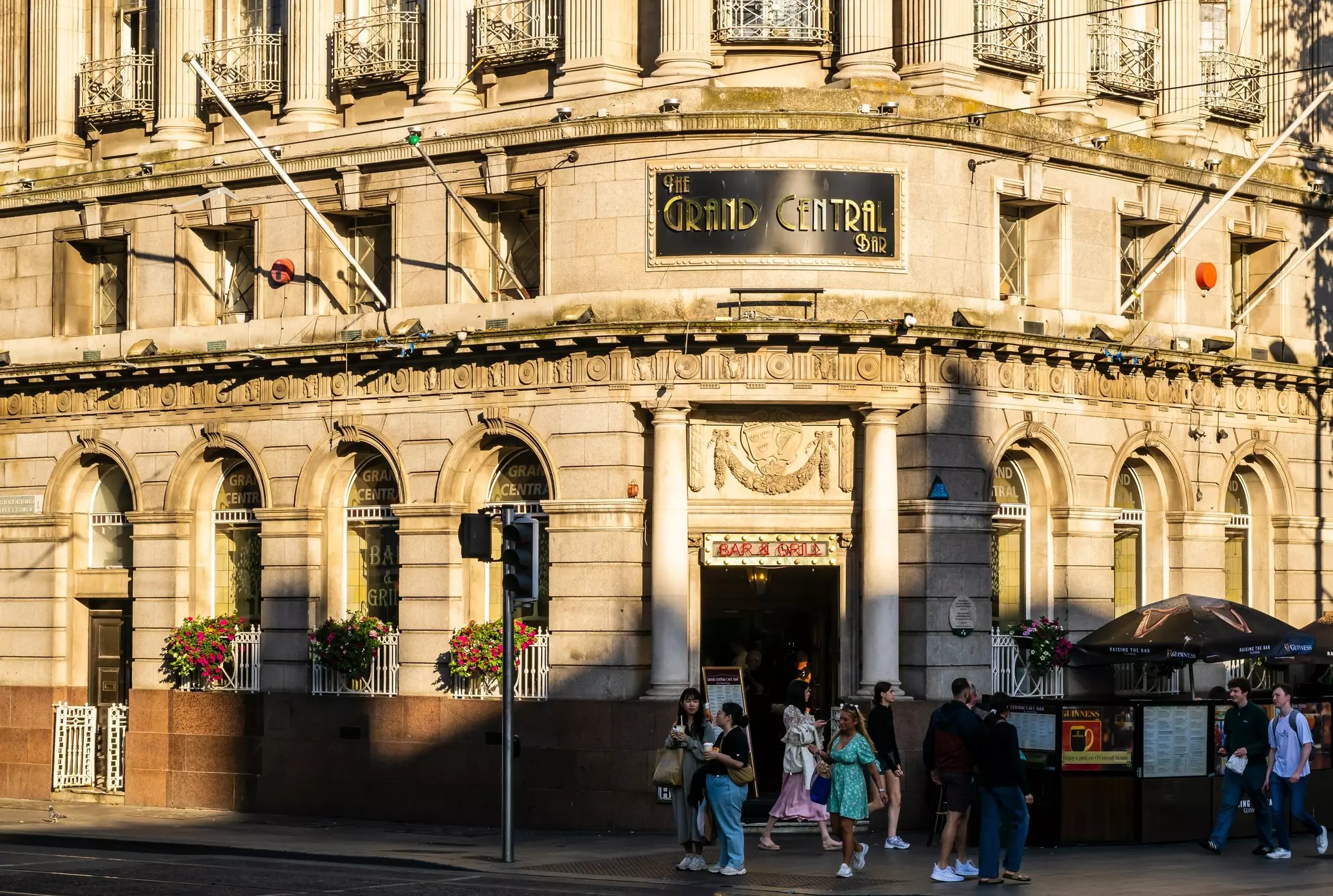 Large sonte building on a corner with a sign reading "The Grand Central Bar" on a sunny day.