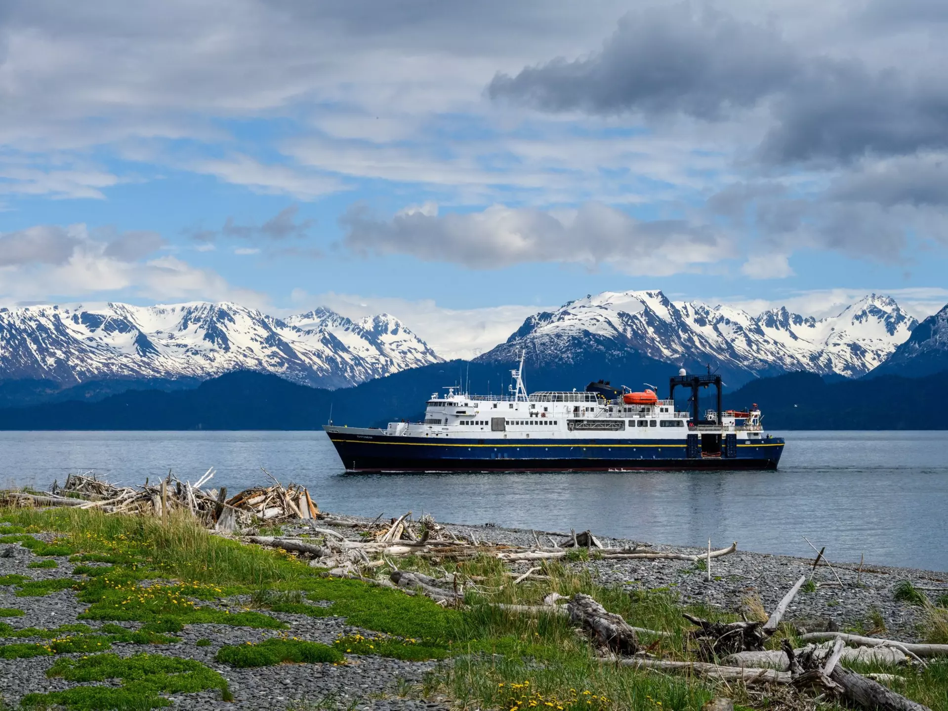 A passenger ferry on the Alaska Marine Highway sailing past snow-capped mountains. knelson20/Shutterstock