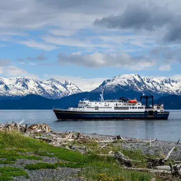 A passenger ferry on the Alaska Marine Highway sailing past snow-capped mountains. knelson20/Shutterstock