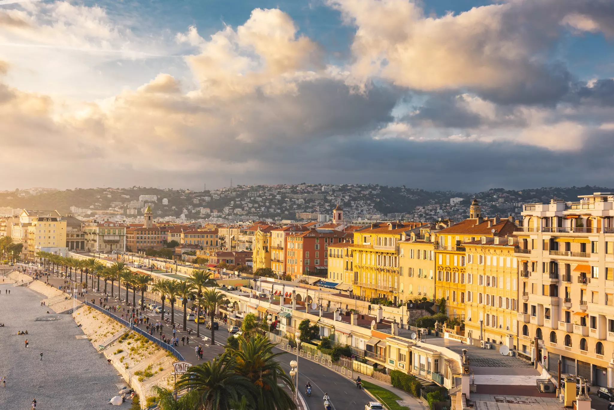 An aerial view of grand buildings and rows of palm trees fronting the beach on the Promenade des Anglais, Nice, Côte d’Azur, France