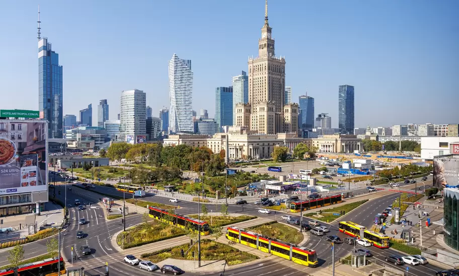 Yellow and red trams crossing a busy roundabout below the Palace of Culture and Science and glass skyscrapers, Warsaw, Poland
