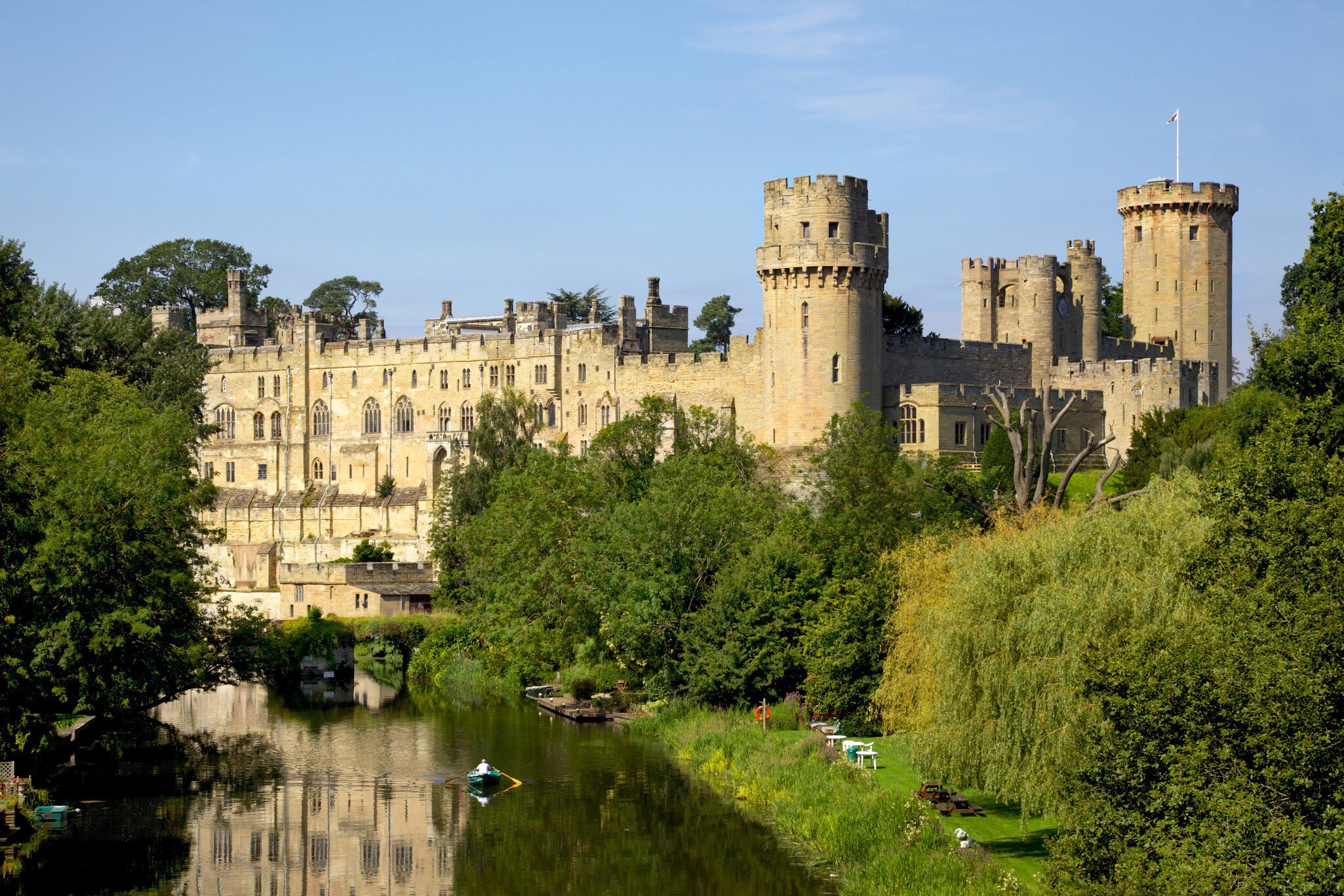 Medieval castle towers and battlements rising above a river and trees.