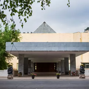 A modern museum entrance with a flat canopy, square pillars and bear statues.