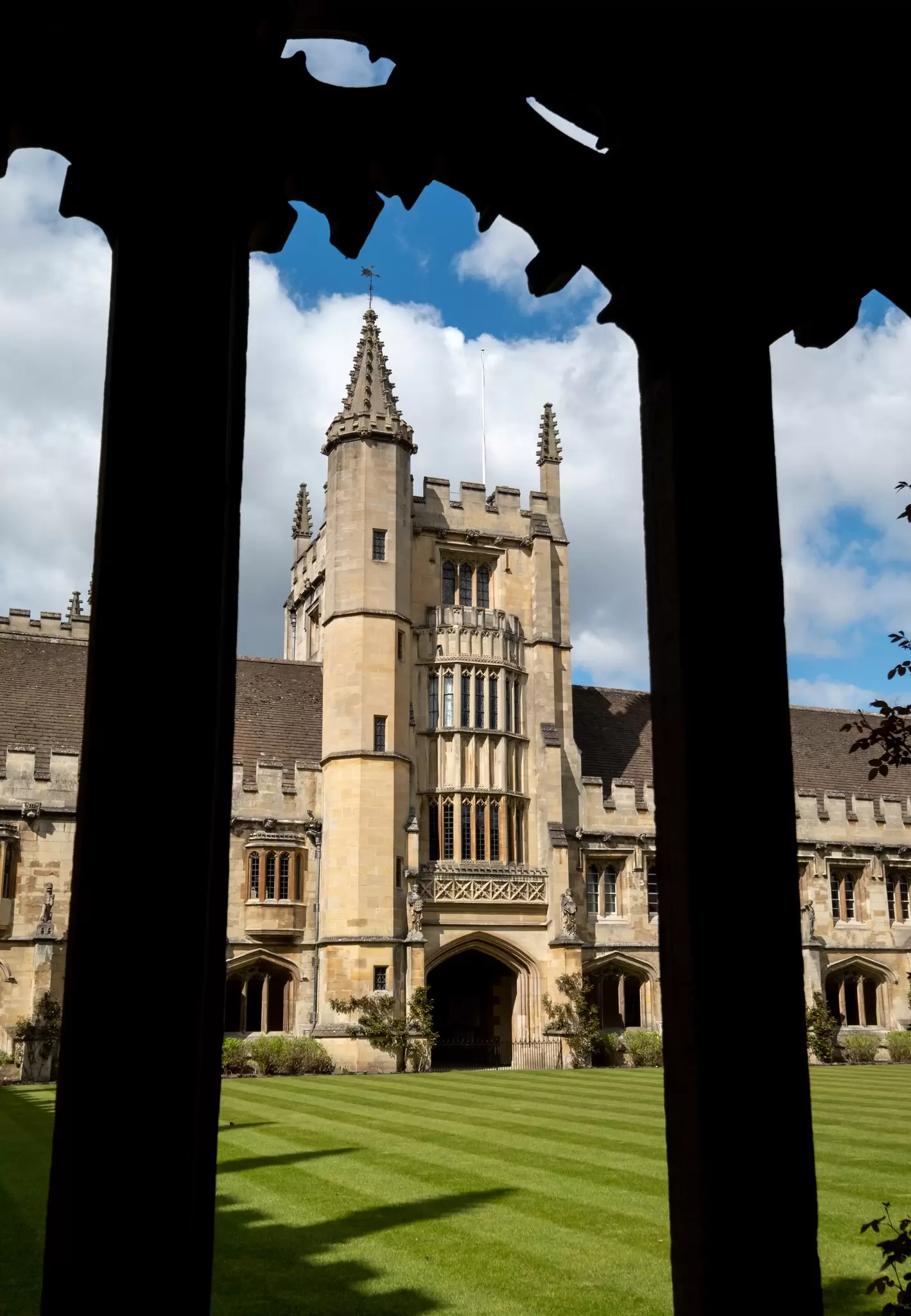 A view of a gothic tower through an arched window at a university.