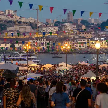 Revellers fill the streets during an evening festival beside a river.