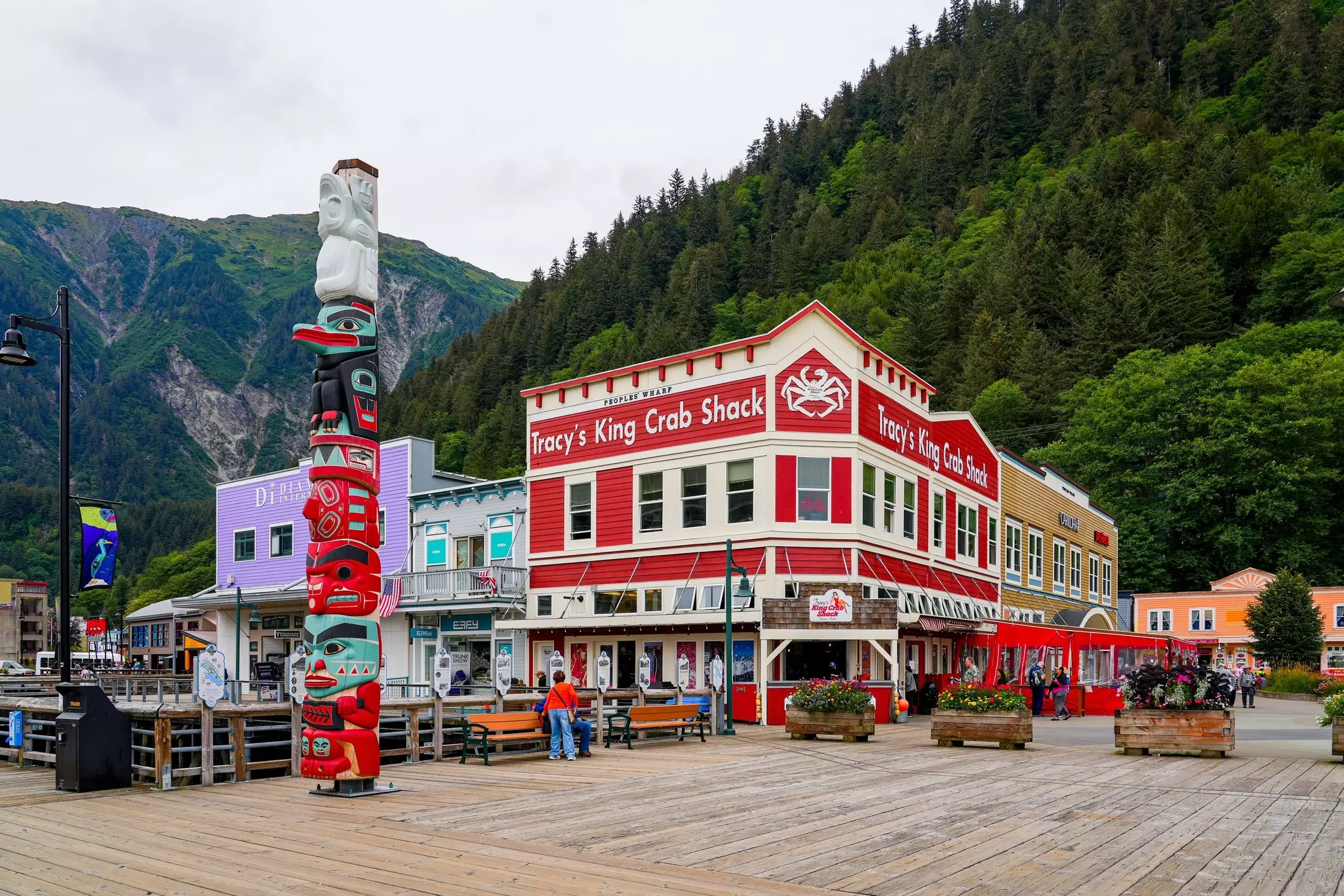A corner building on a boardwalk with a totem pole standing nearby.