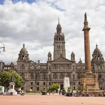 An ornate building on Glasgow's George Square with people milling about.