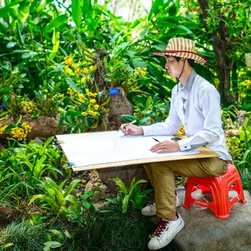 A young man painting sketch in Xishuangbanna Tropical Botanical Garden, Chinese Academy of Sciences. Located in Menglun Town, Mengla County, Yunnan Province, China.