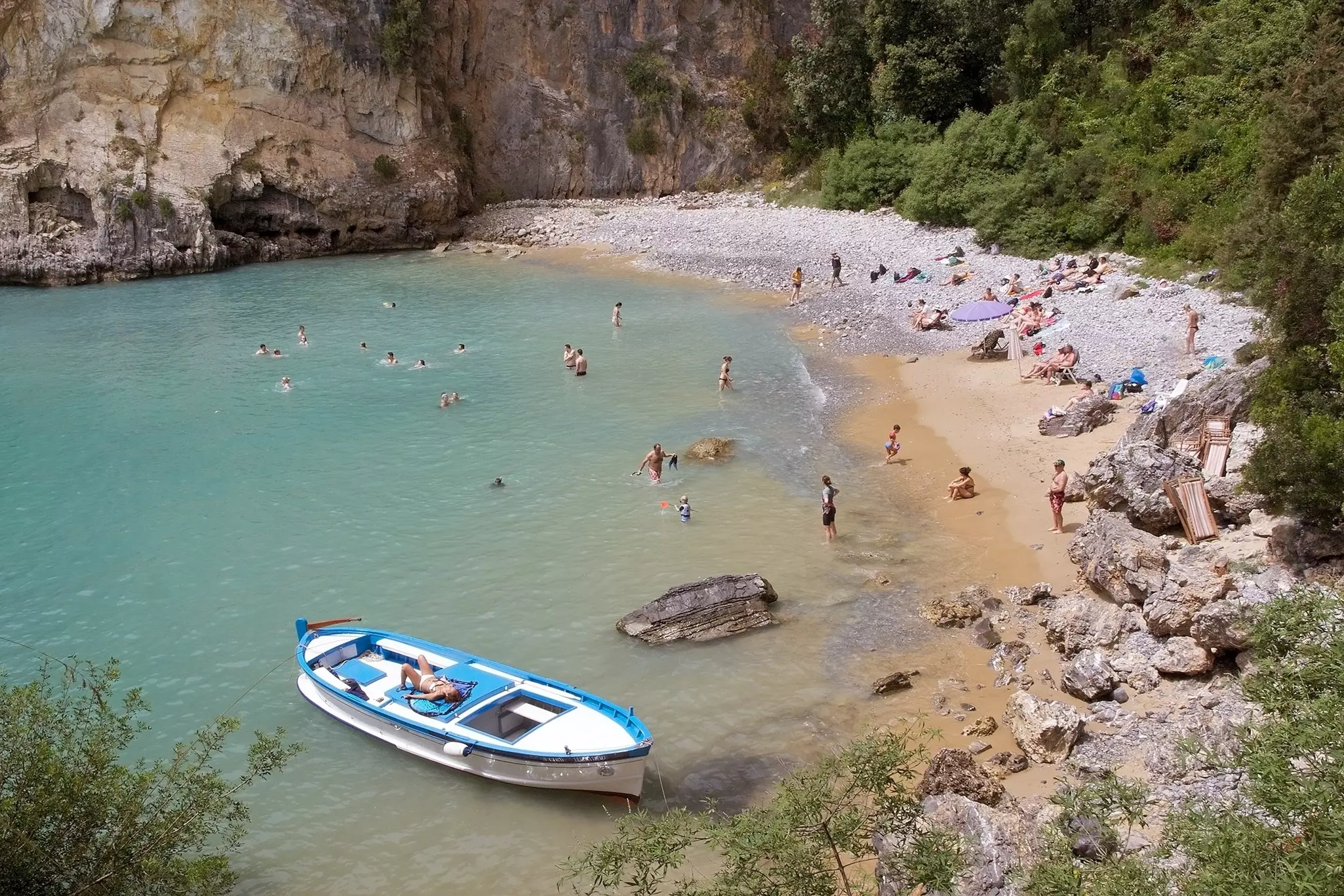 Tourists on a beach with a boat