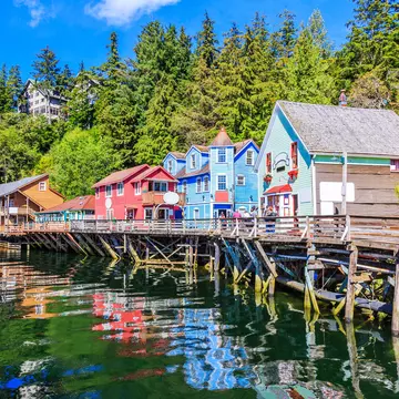 A wooden boardwalk in front of harborfront homes and shops on a sunny day