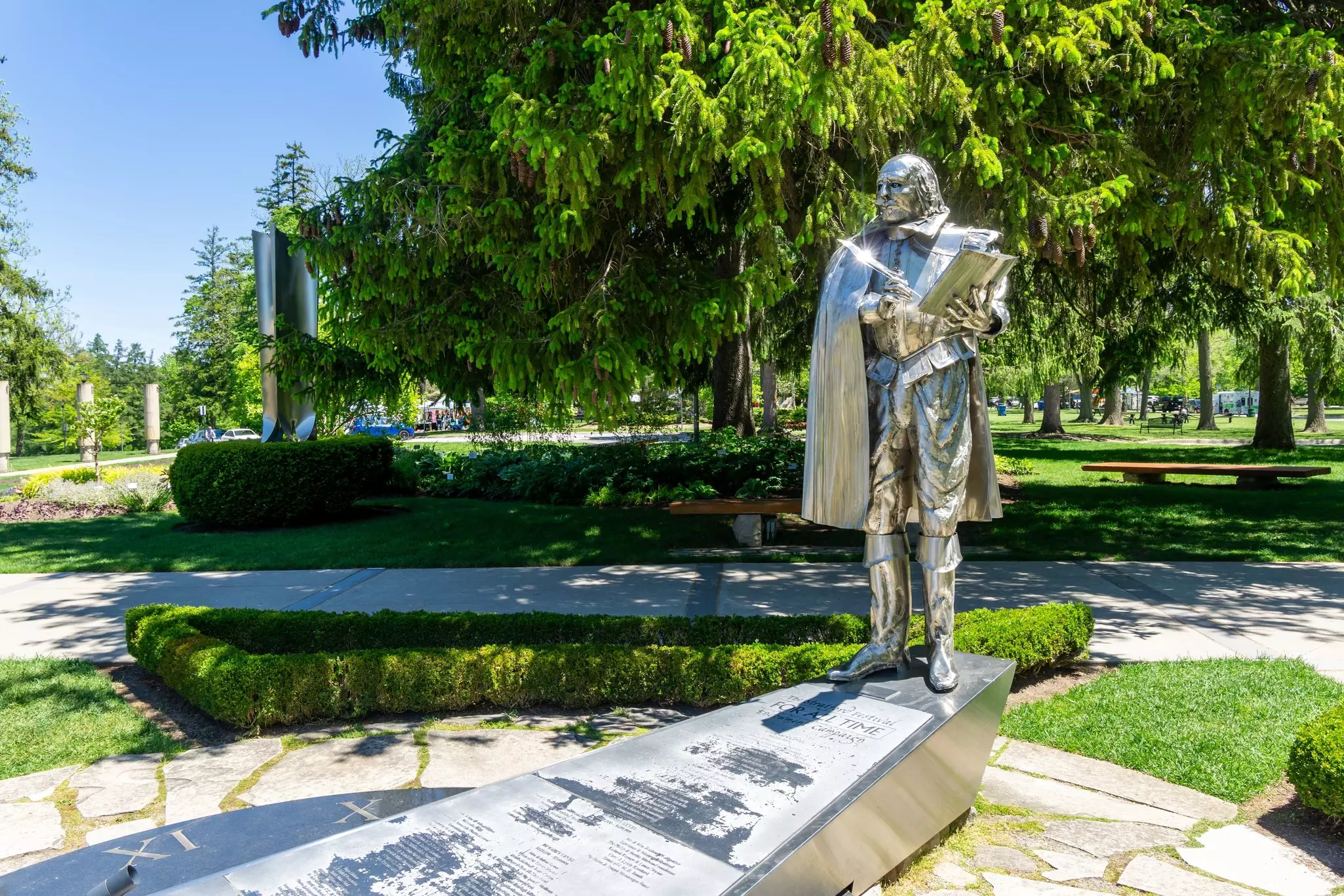 A metallic life-size statue of a writer stands in a public park in Stratford, Ontario