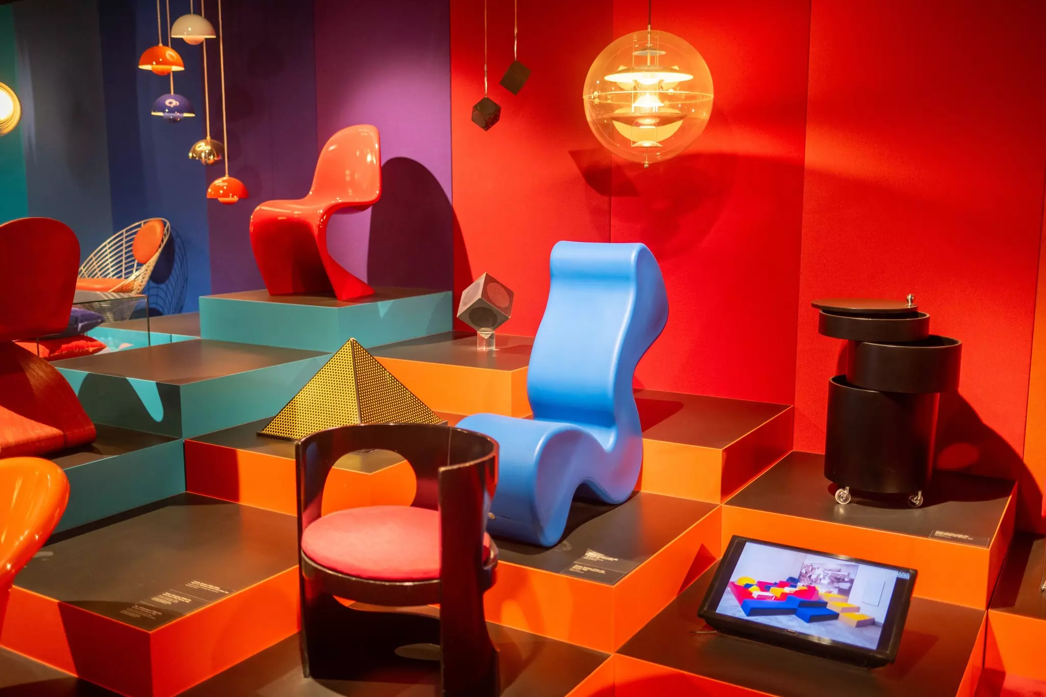 Colorful chairs in a modern design on various levels of platforms in a museum.