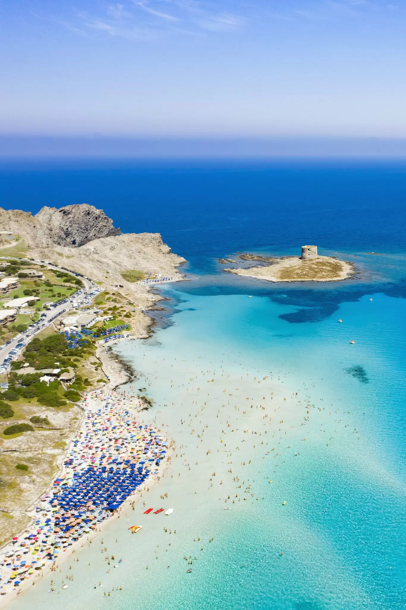 Stunning aerial view of the Spiaggia Della Pelosa (Pelosa Beach) full of colored beach umbrellas and people sunbathing and swimming in a beautiful turquoise clear water. Stintino, Sardinia, Italy., License Type: media, Download Time: 2025-10-06T16:03:32.000Z, User: katelyn.perry_lonelyplanet, Editorial: false, purchase_order: 65050 - Digital Destinations and Articles, job: wip, client: wip, other: Katelyn Perry