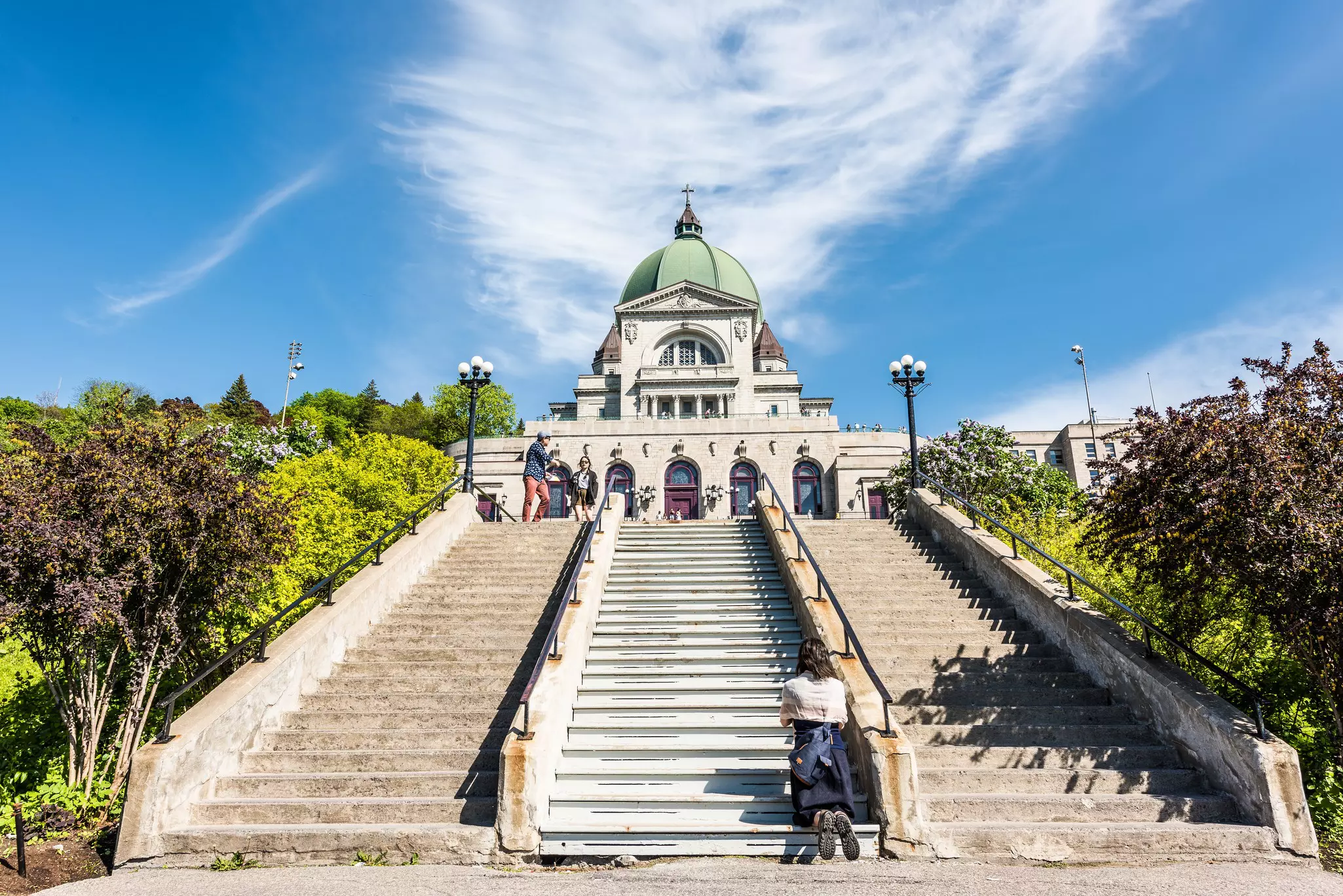 A woman kneels in prayer on the steps leading up to Oratoire St-Joseph, Montréal, Québec Canada