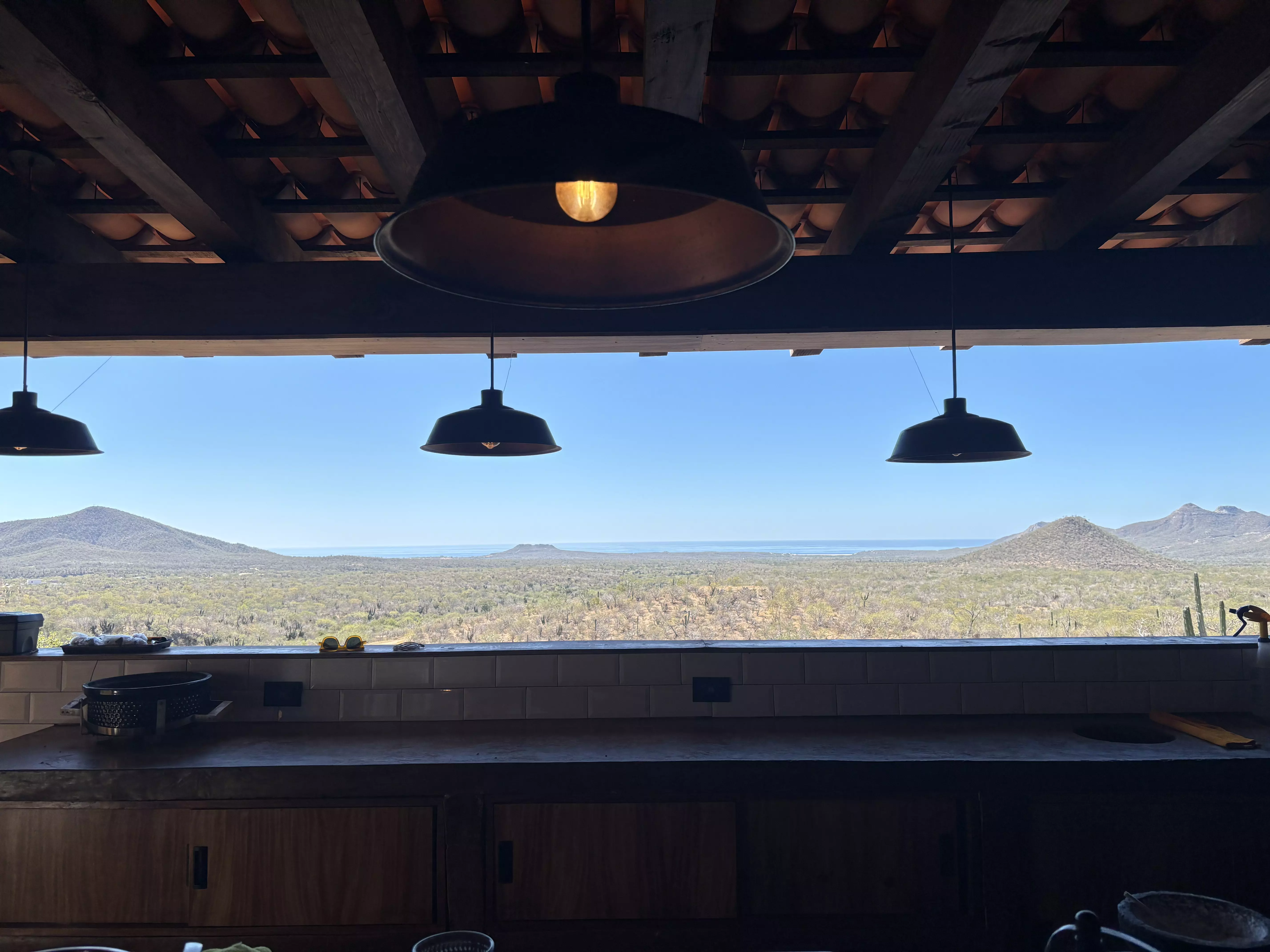 Lights hang above a window that frames a view of a desert landscape.