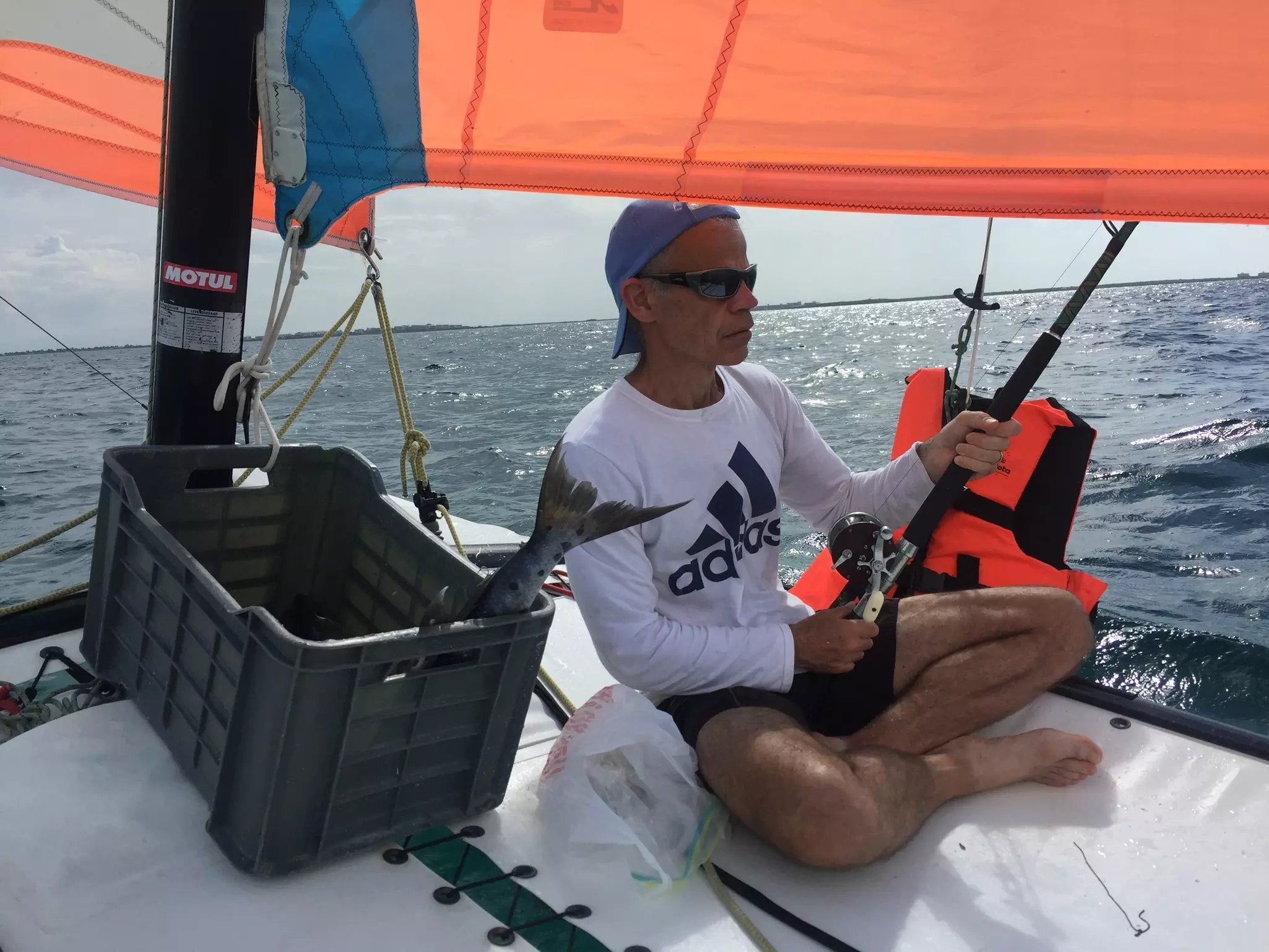 A man sitting on a sail boat with a fishing rod