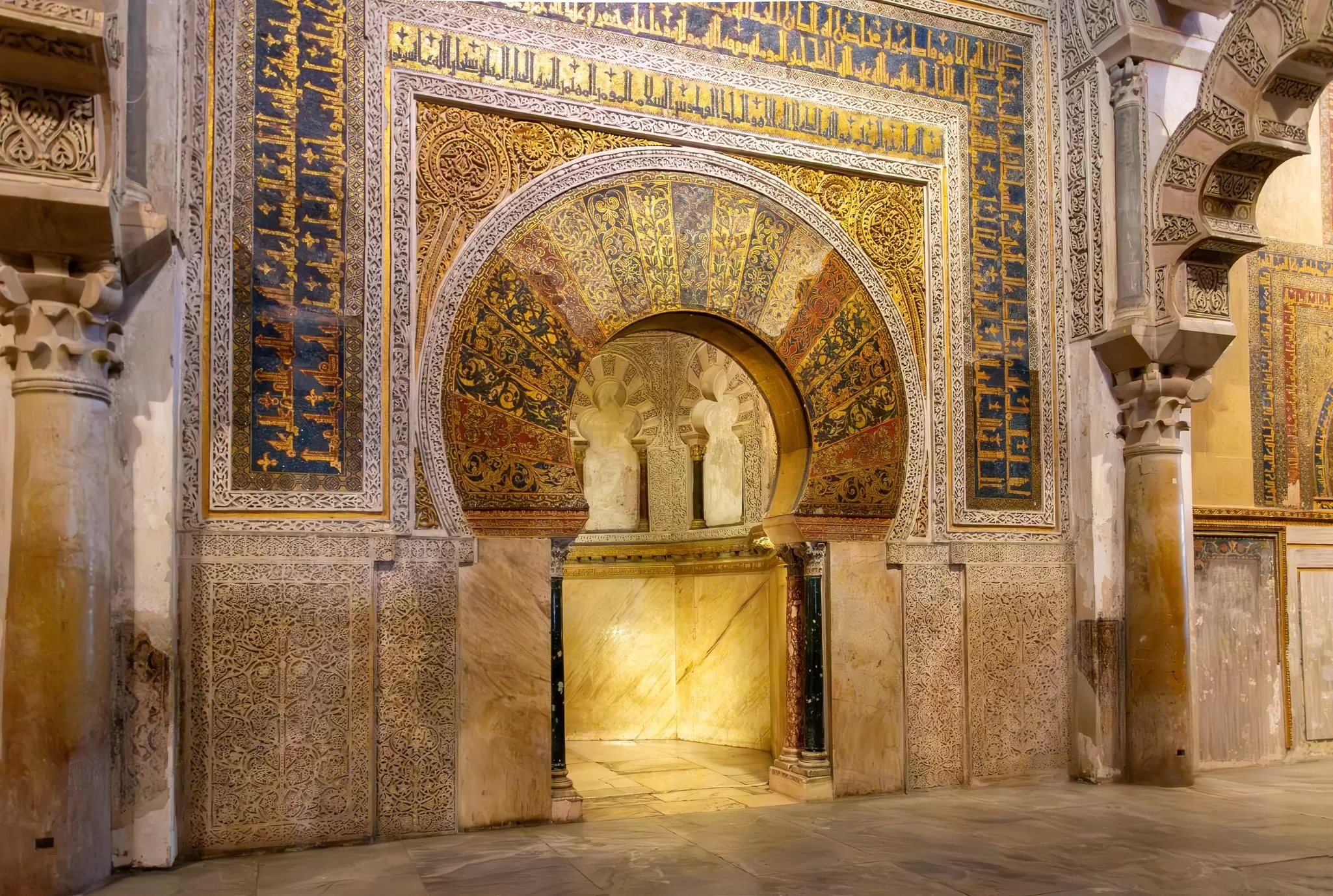 View of the golden arched mihrab (prayer niche facing Mecca) inside the Mezquita in Córdoba, Spain.