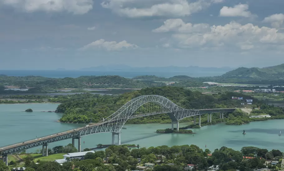Bridge of the Americas, a steel arch bridge in Panama, spanning green water with forested hills and Pacific islands beyond