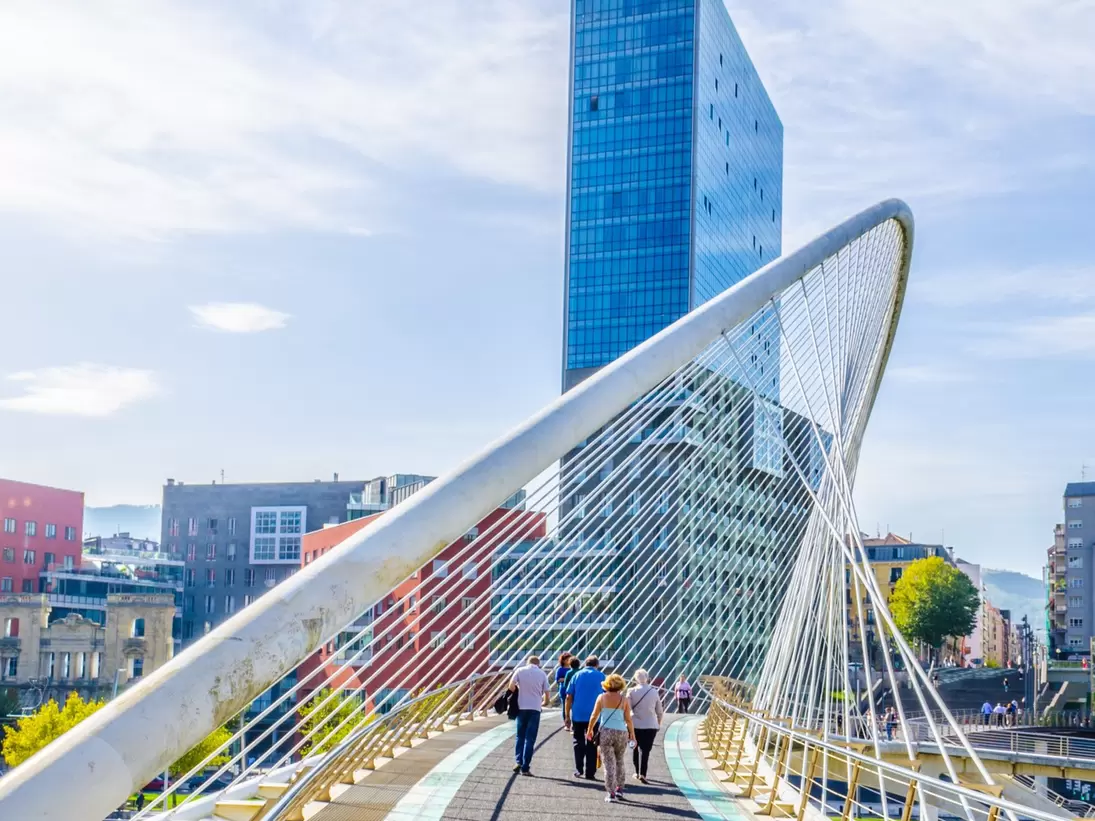 People crossing the Zubizuri bridge on a sunny day in Bilbao, Spain.