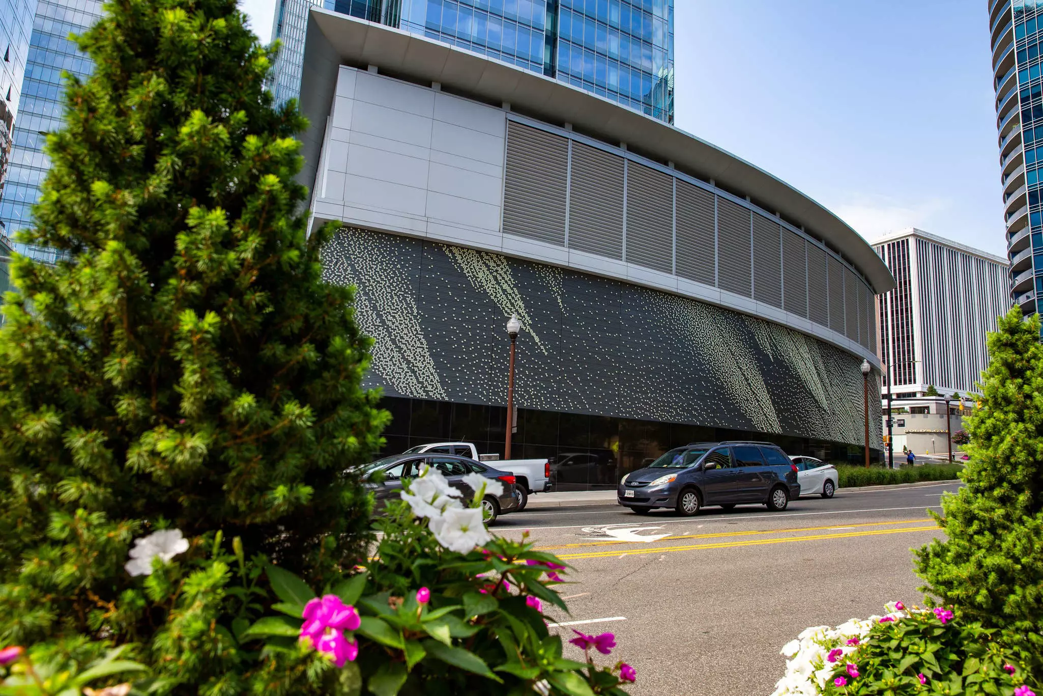 Public art in Rosslyn, with blooming flowers in the foreground and cars driving by