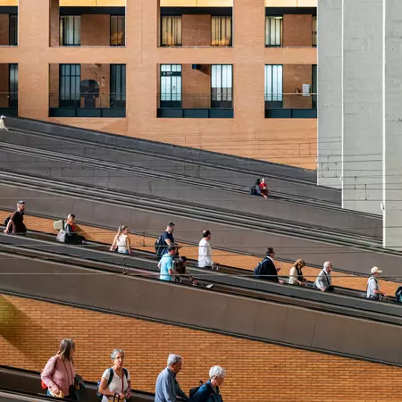 Passengers on moving walkways heading down into a station.
