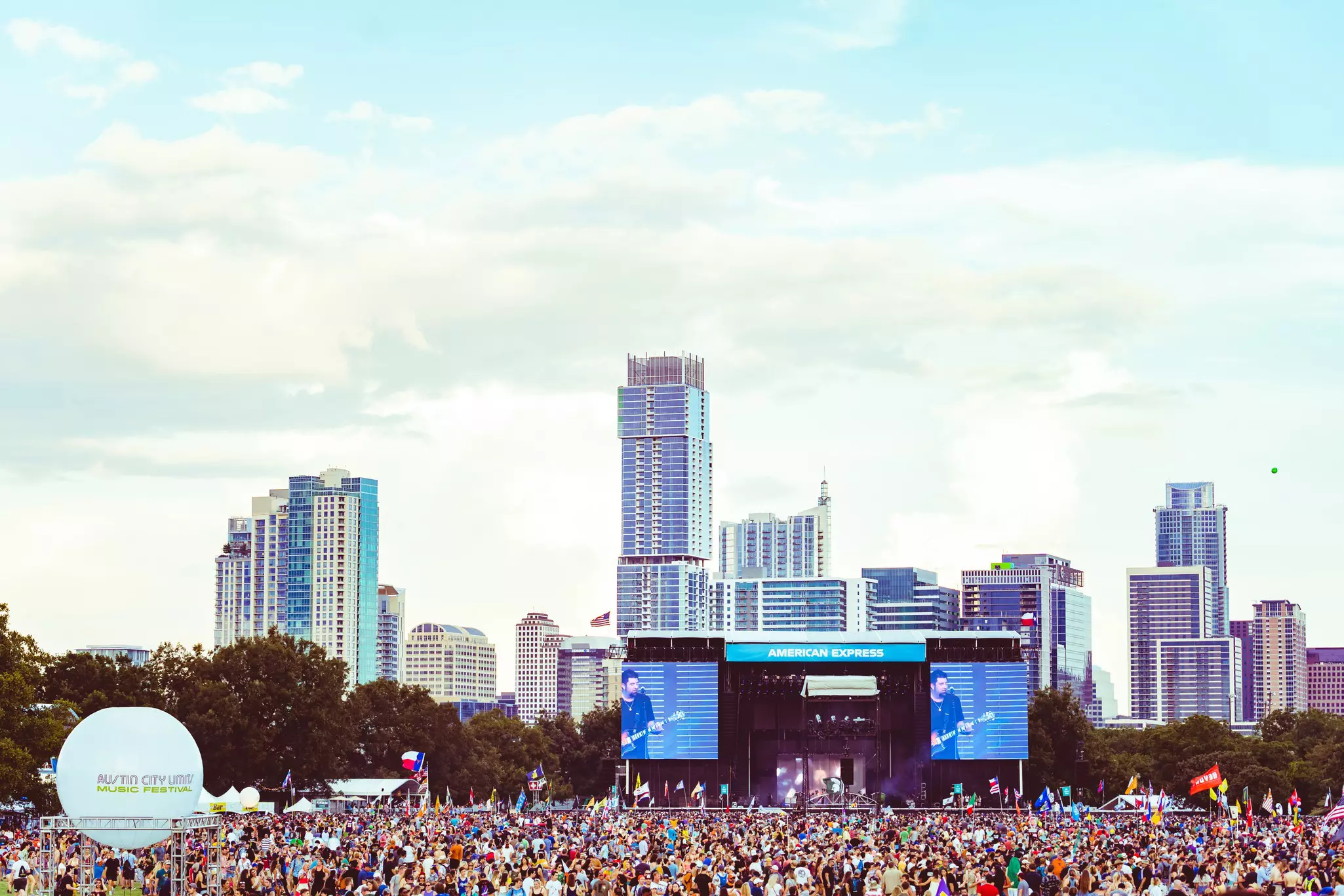 Crowd watching a concert in a park near a downtown area