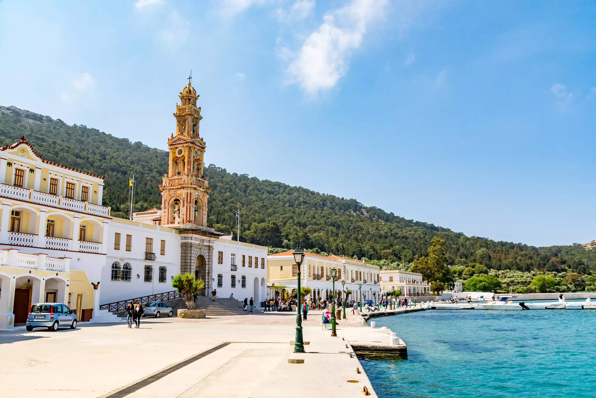 An empty promenade by the water in a small town; one of the buildings has an elaborate spire.