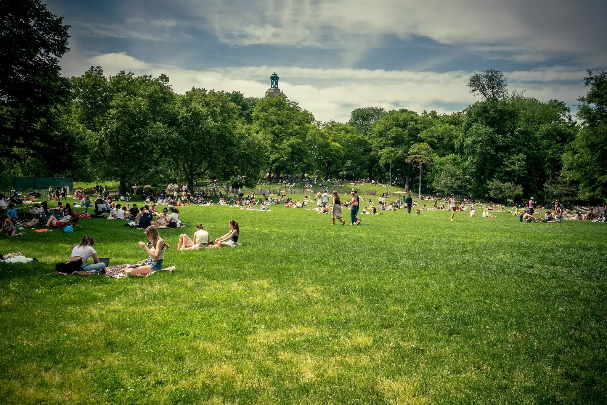 People relax, chat and hang out in groups on the grass in a large park