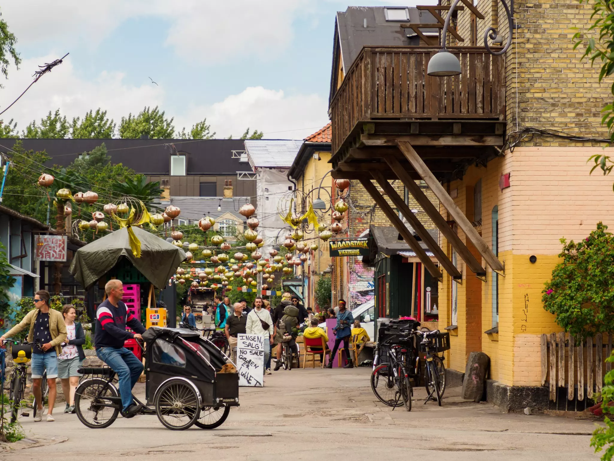 A street with lanterns hanging across it in the Christiania community in Copenhagen, Denmark