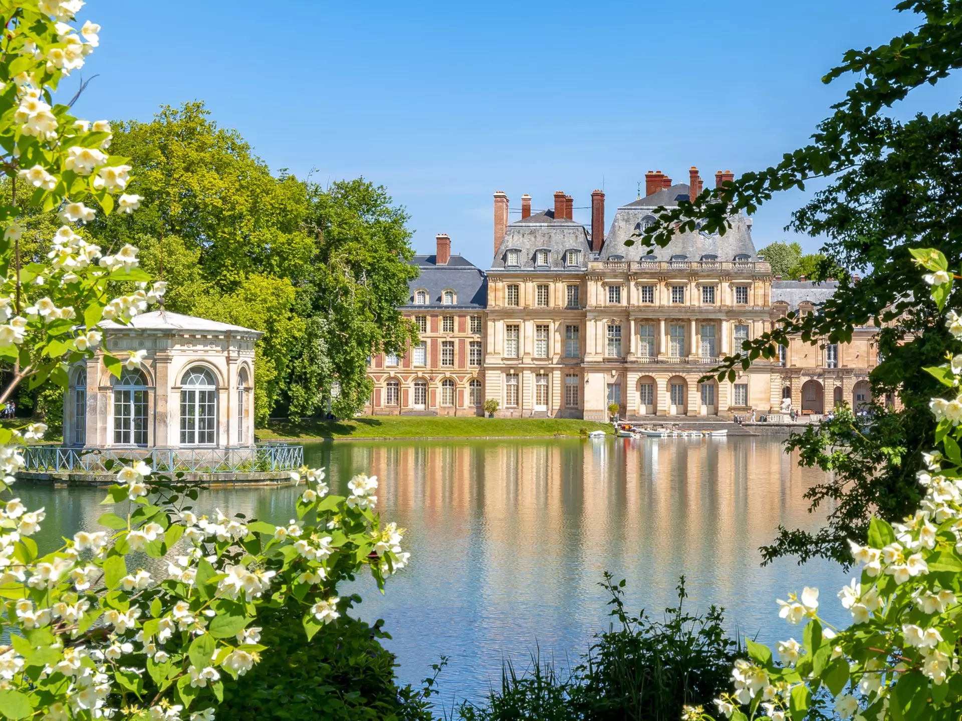 A vast palace next to an ornamental lake with small row boats.