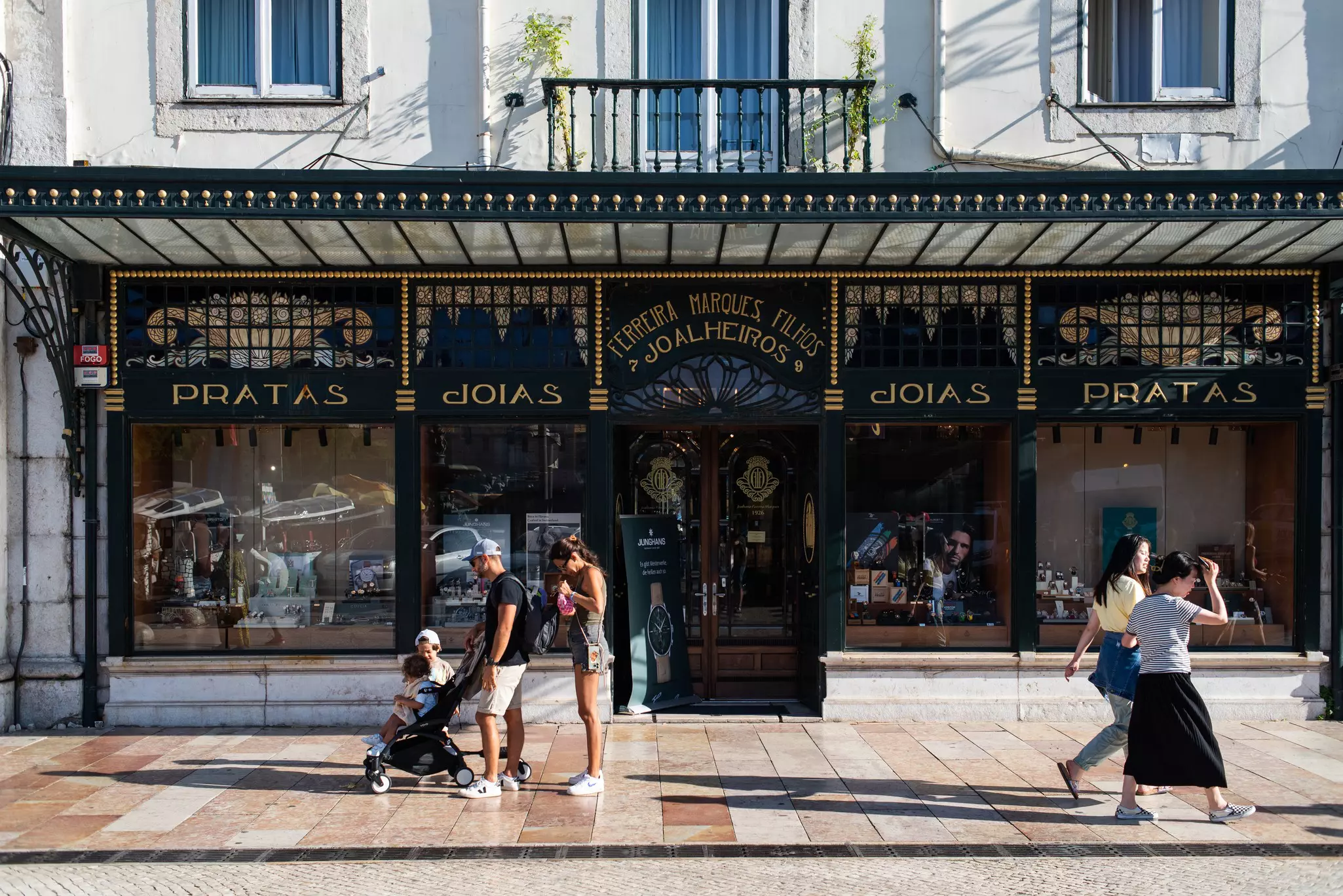 A family with a few children and a stroller stop on the sidewalk in Baixa, Lisbon.