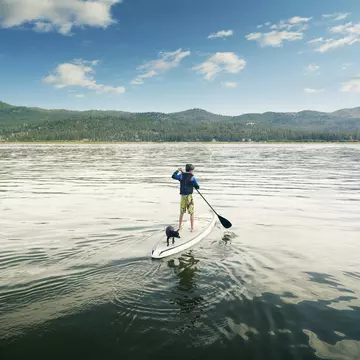 A boy and his dog paddle boarding on Big Bear Lake, San Bernadino County, California