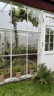 A white paned window looks in on a table for two in a garden shed.