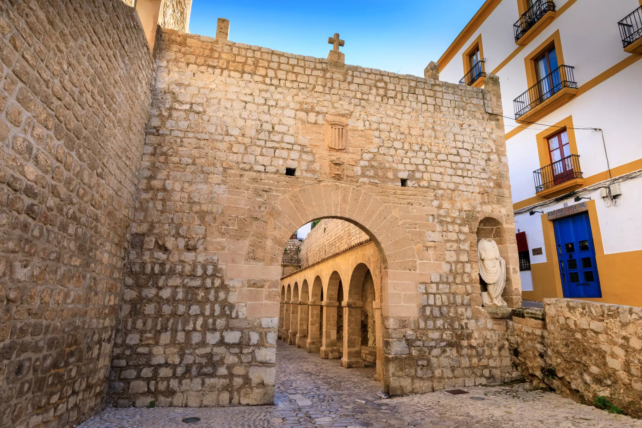 A historic stone wall with arched portal is pictured in an old city.
