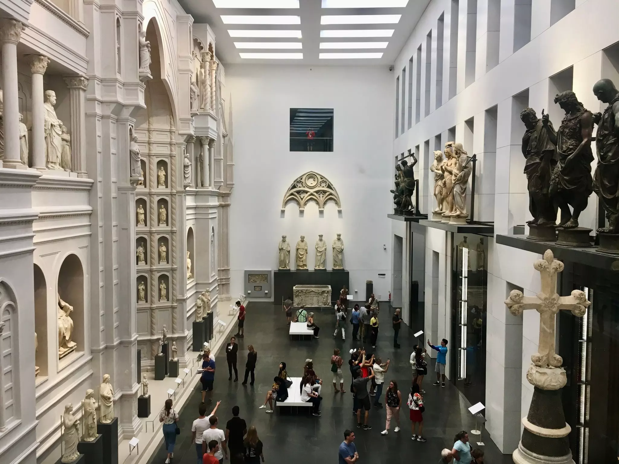 Visitors move around a large display area filled with religious art and sculptures.