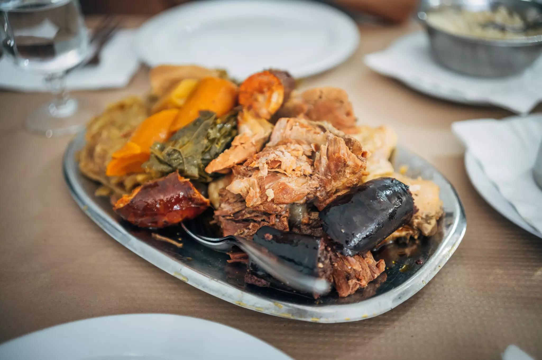 A dish of meat, taro, potatoes and other vegetables on a wooden table