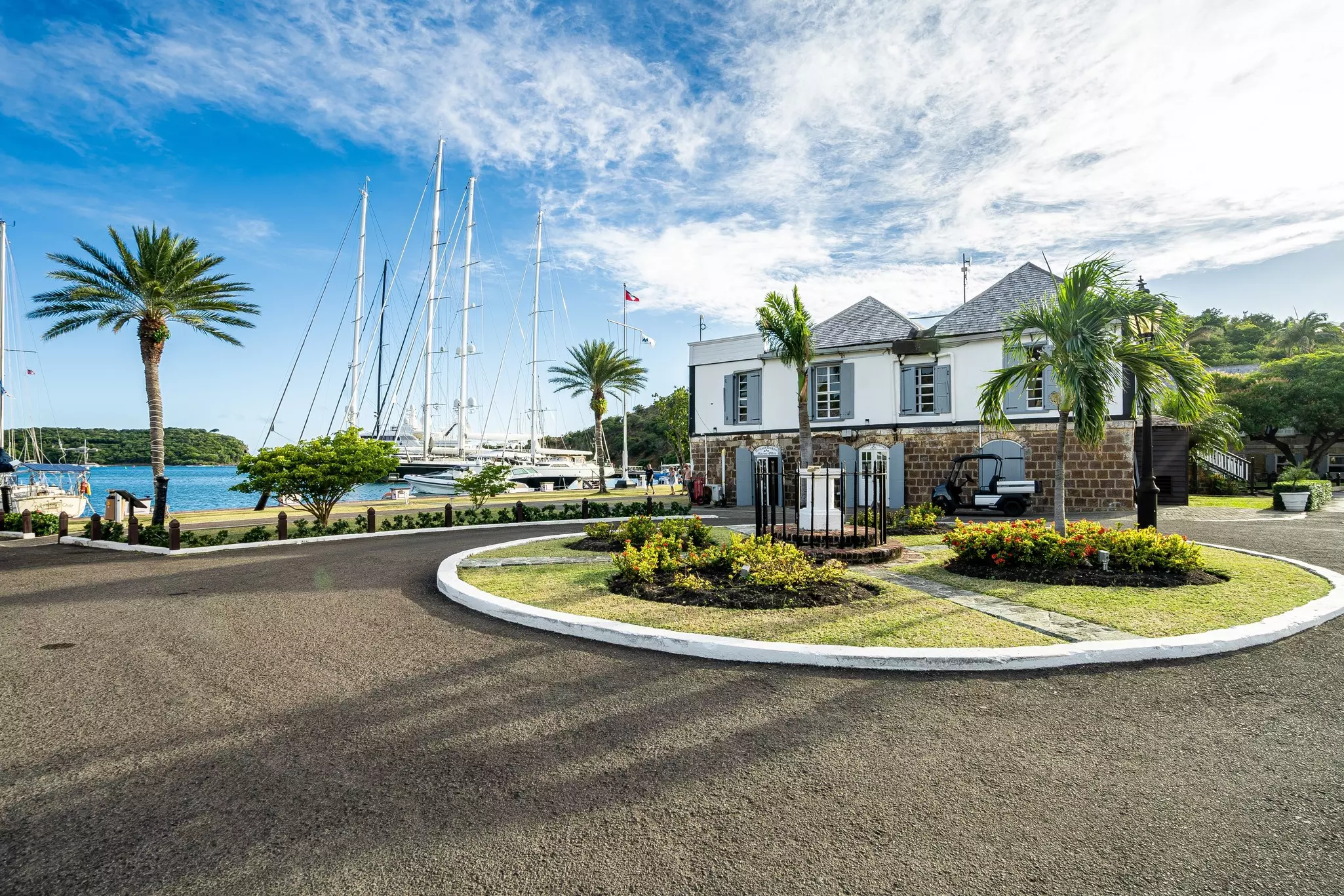 A picturesque harbor with several large boats docked in it. A historic Georgian building stands at the water's edge.