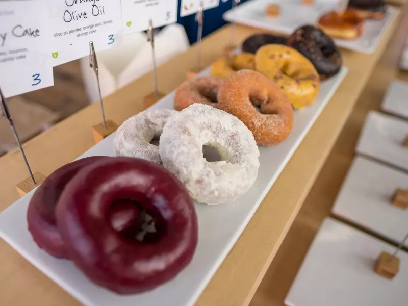 A plate of doughnuts on display in a doughnut shop.