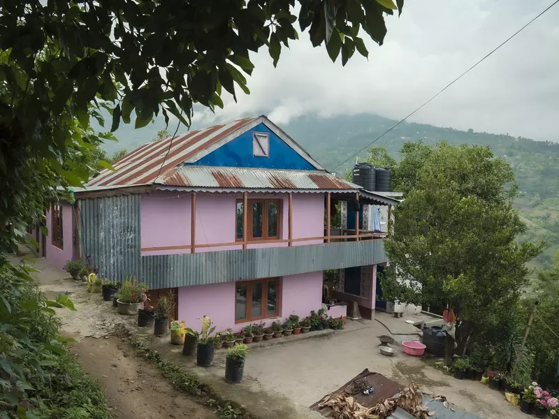 A pink house in Nepal; a mountainscape is in the background.