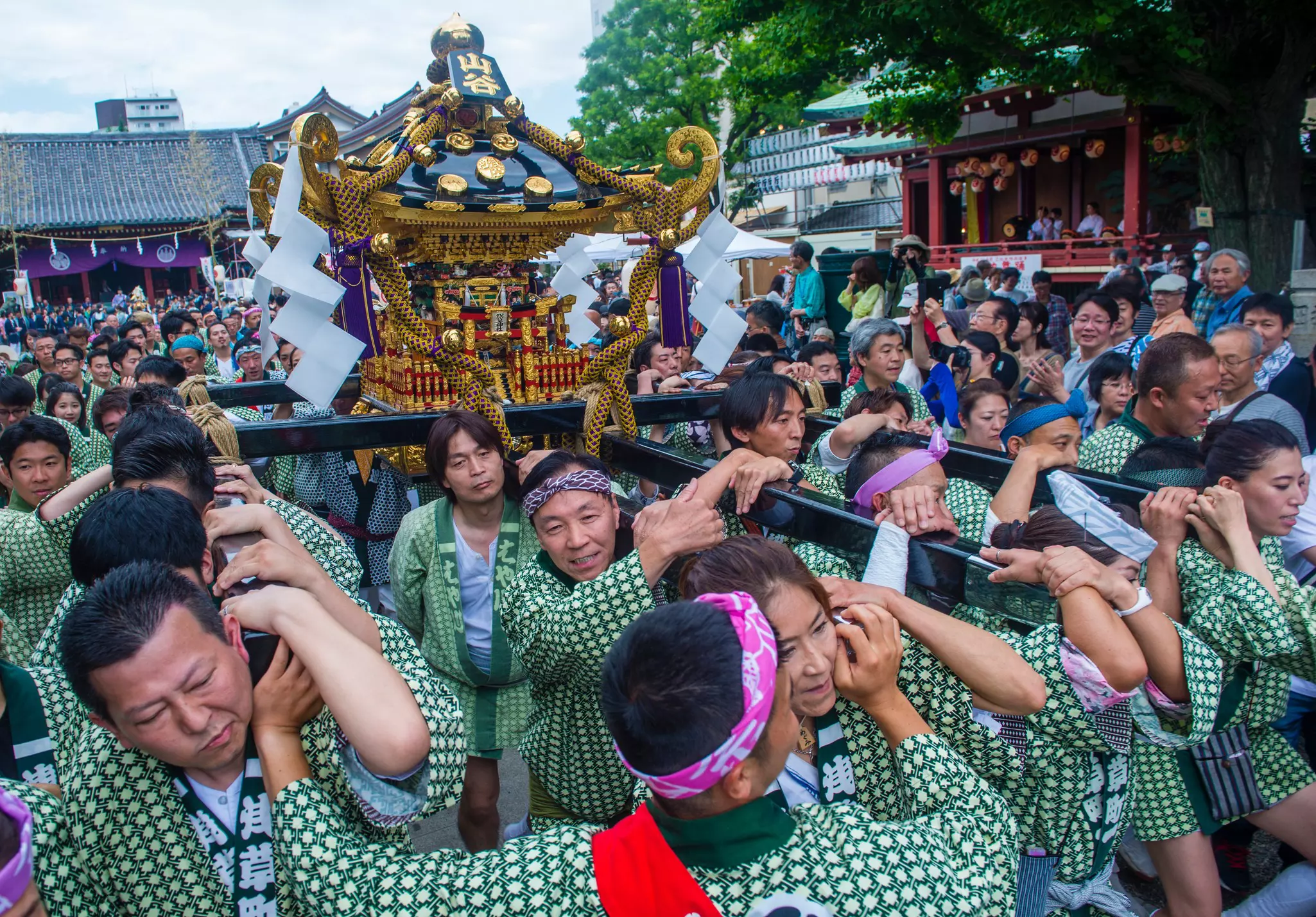 Participants in the Kanda Matsuri in Tokyo, wearing matching traditional clothing and carrying a colorful float