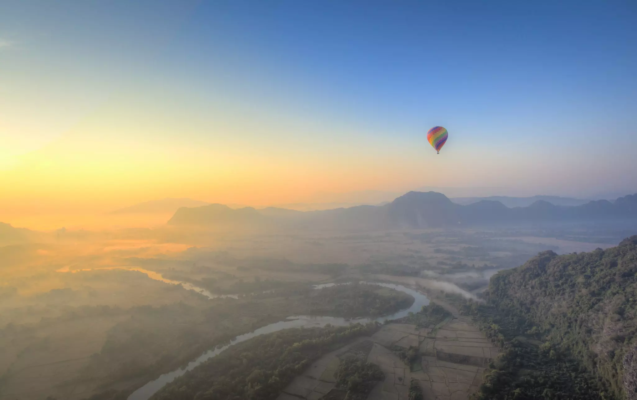 A hot air balloon flying over the Karst mountains, Vang Vieng, Laos. 