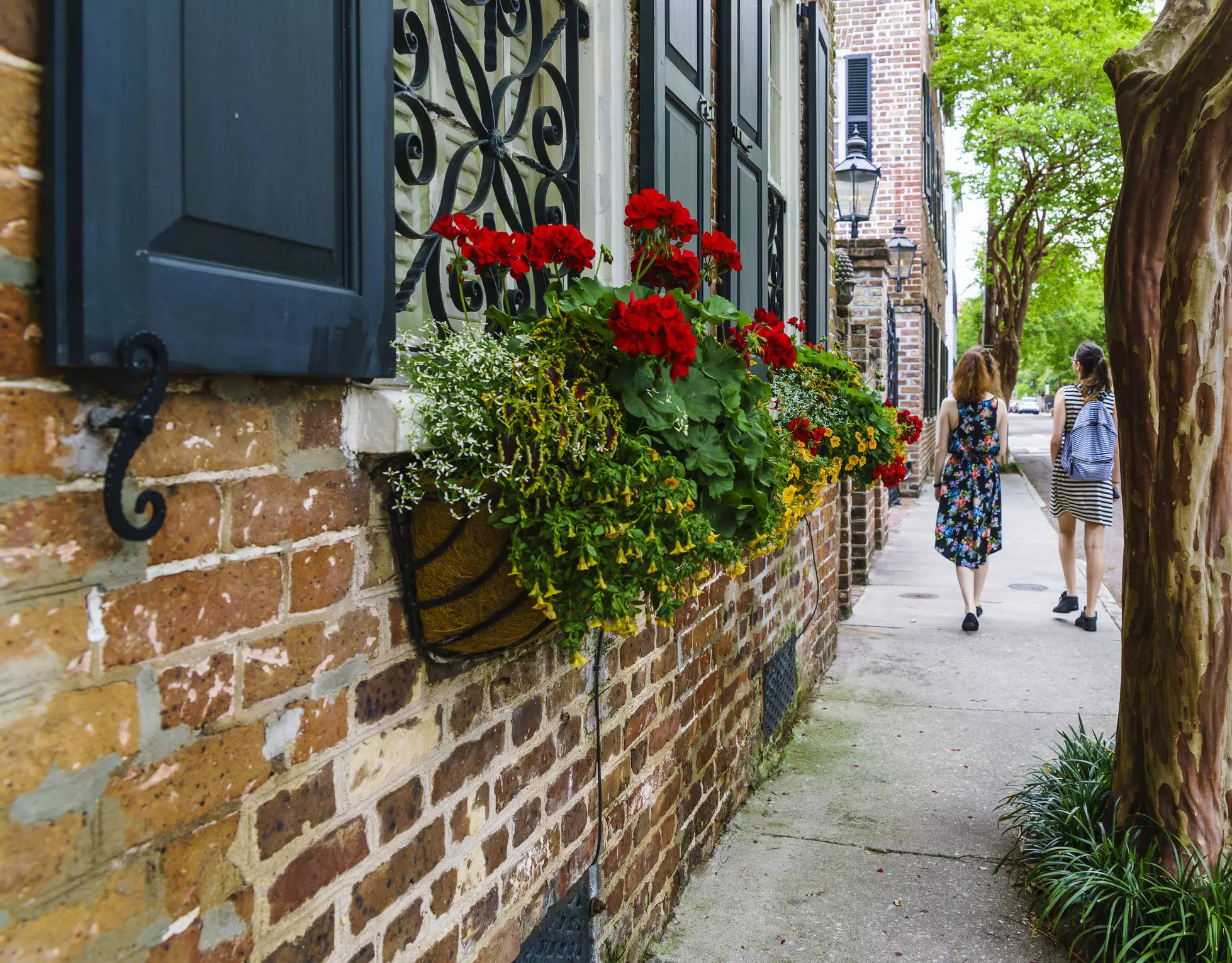 Two teenager girls, tourists with binoculars, exlore the street in the historic old city of Charleston, South Carolina