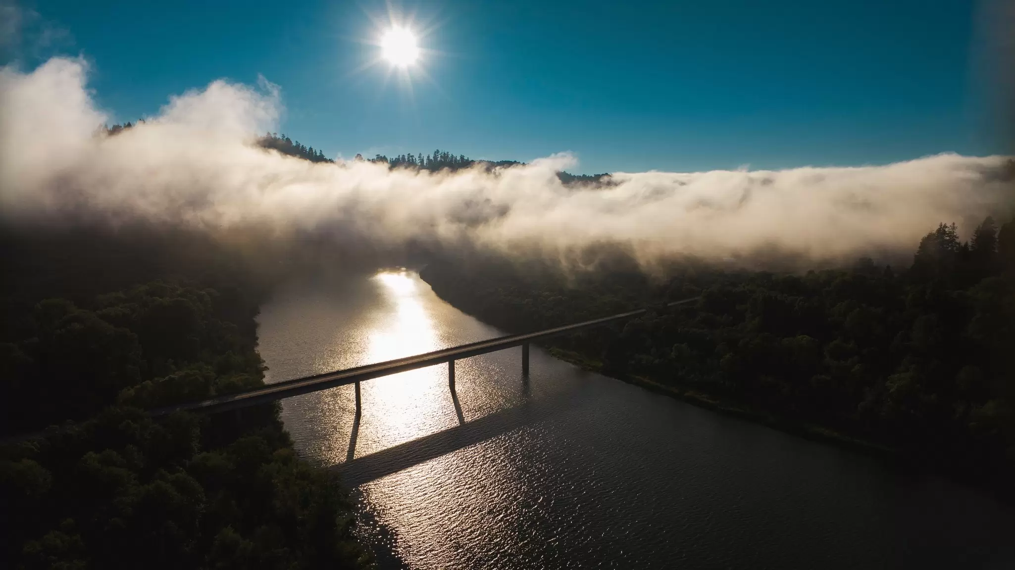 A view of a bridge across a river, with mist below a blue sky, Northern California