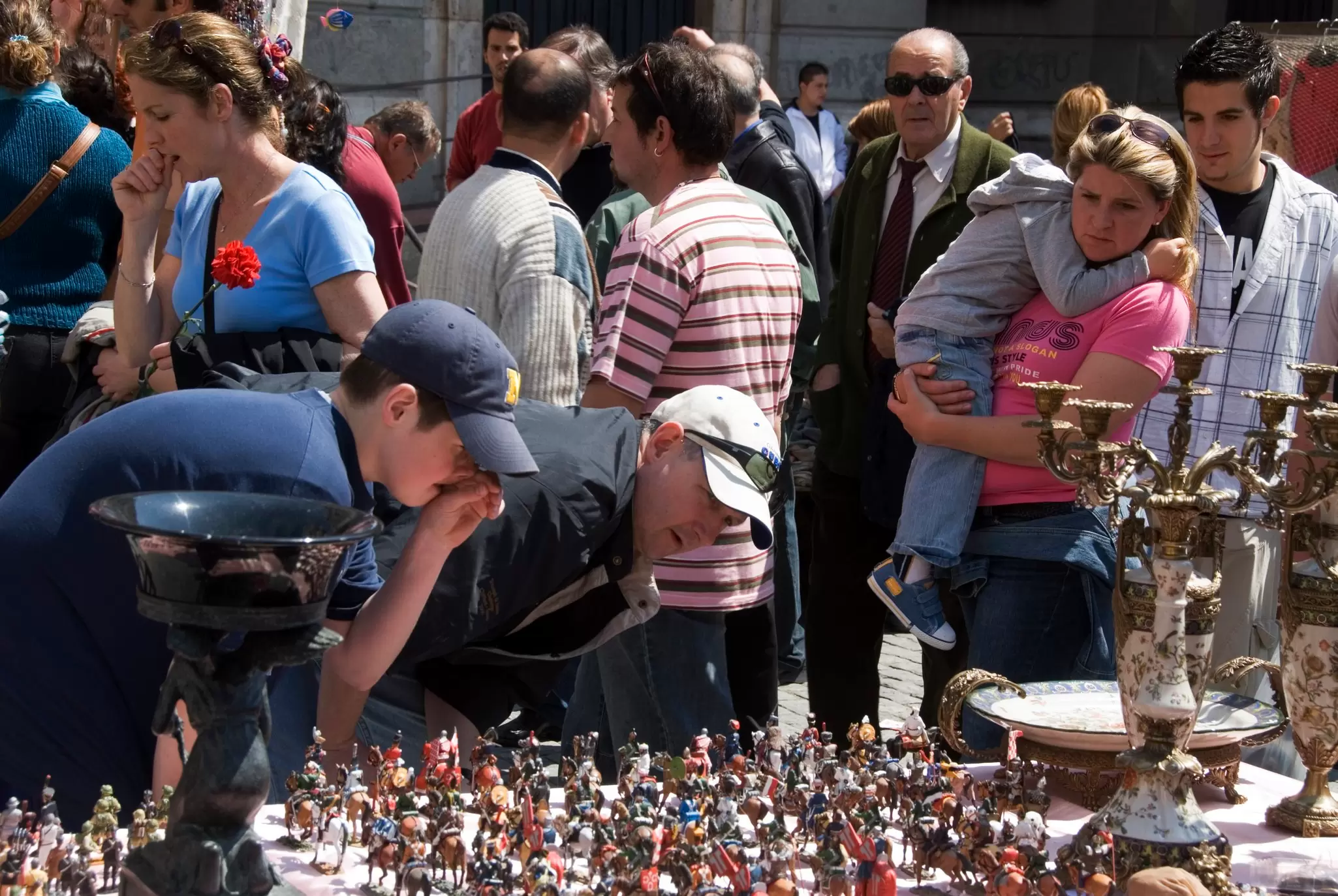 People looking at an antique stall at the El Rastro flea market, Madrid. 