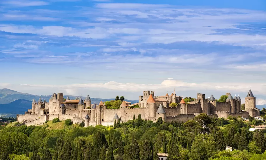 Medieval walled city of La Cité in Carcassonne, France, with pointed towers and double ramparts above cypress woods