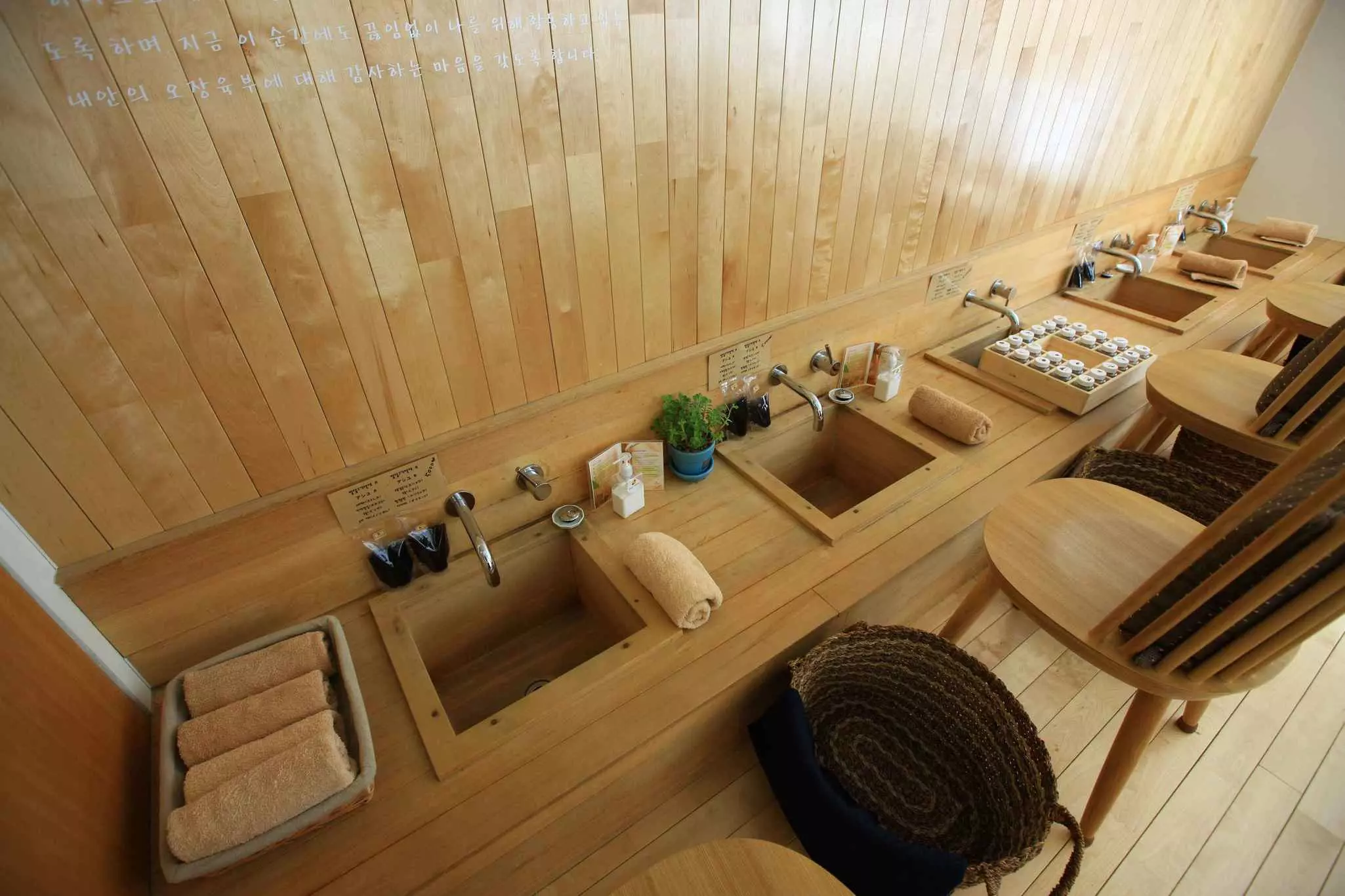 A row of low-level sinks in front of chairs for people to place their feet in for treatments in a spa.