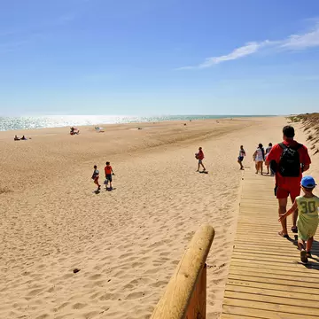 El Rompido, Spain - Sep 6, 2010: A family on the wooden walkway on way to the beach of La Flecha del Rompido, beaches of Huelva, Andalusia, Spain; Shutterstock ID 1265961751;